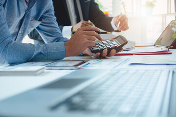 Fototapeta premium Businessmen analyzing investment graphs, brainstorming meeting and discussing plans in conference room. Using graph sheets, laptops and calculators. business and investment ideas