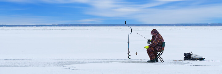 Fototapeta na wymiar Ice fishing. lonely man fishing for perch. Winter fishing as hobby, Winter activity in Scandinavia. Hobby, winter free time concept