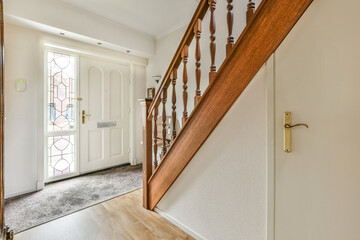 an entry way leading to the front door and stairs in a white house with wood railings on both sides