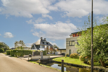 a house on the side of a road with water running through it and trees in the fore - eyed view