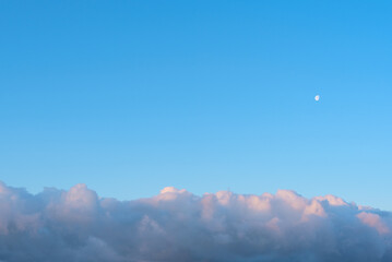 Bright blue sky with white fluffy clouds and the Moon. Beauty of nature. Aerial natural background