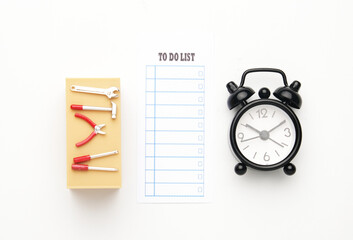Flatlay picture of tools miniature on office desk miniature, alarm clock and to do list paper.