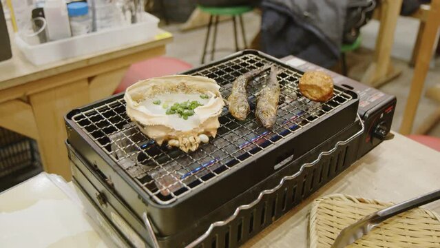 Crab miso brains and fish grilled on gas stove. Japanese cuisine. Slow motion footage filmed with BMPCC 6K