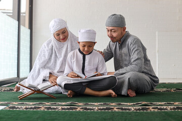 Traditional muslim family parents with children reading Quran and praying together during a ramadan...