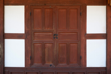 Red brown wooden door frame on white wall. Korean traditional wooden door. Asian old historical wooden door frame.