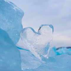 Arctic landscape with a transparent icy heart, frozen snow of Lake Baikal or extreme Antarctica. An icicle in the shape of a heart on ice. An icy heart. Selective focus.
