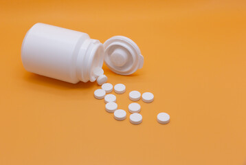A vial with a white lid rolling over an orange background and several white round pill painkillers flowing and scattered from it.