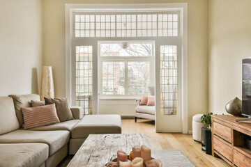 a living room with couch, coffee table and television set in front of large window looking out onto...