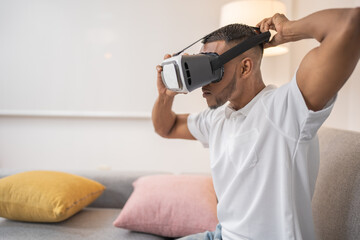 Young man, wearing virtual reality glasses in the living room of his apartment.