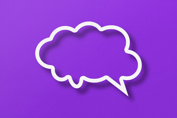 White paper cut out speech bubble shapes set on purple paper background.