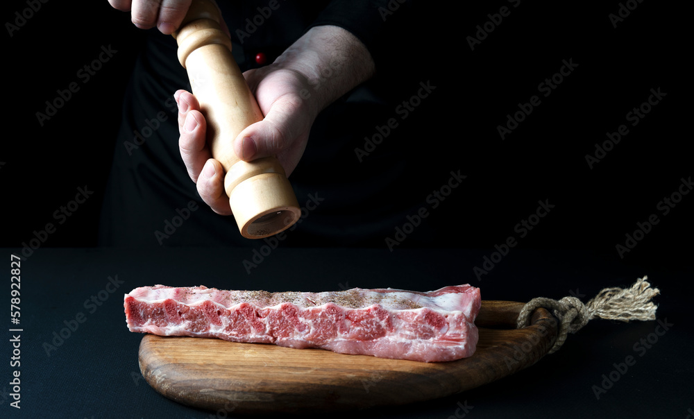 Wall mural the chef sprinkles the meat with spices and salt, the concept of the restaurant menu