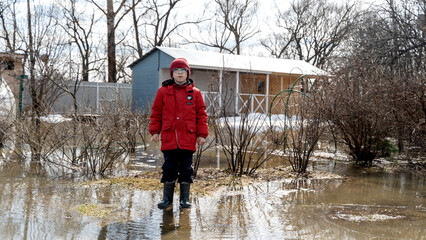 a boy stands at a house flooded in high water