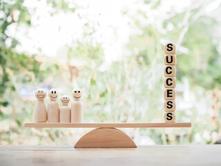 Wooden human figure and wooden blocks with the word SUCCESS on balancing scale for business success...