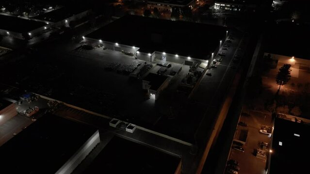 A nondescript industrial warehouse building is shown at night from an aerial, establishing view.