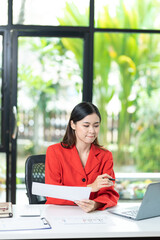 Portrait of pretty cheerful girl smiling while working on laptop in office