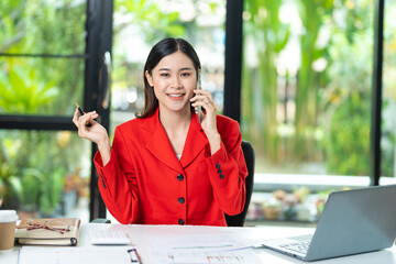 Happy business woman talking on mobile phone while analyzing weekly schedule in her notebook