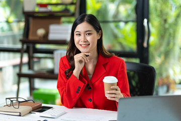 Portrait of pretty cheerful girl smiling while working on laptop in office