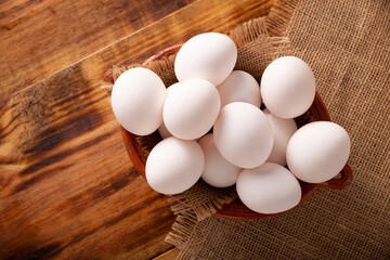 Many white chicken eggs on rustic wooden table. Very popular nutritious and economic food product. Table top view.