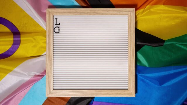 Stop motion LGBTQ description frame on Rainbow LGBTQIA flag made from silk material. LESBIAN, GAY, BISEXUAL, TRANSGENDER, QUEER. Symbol of LGBTQ pride month. Equal rights. Peace and freedom. Support