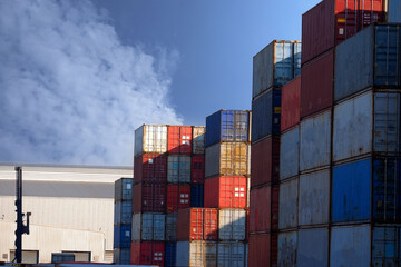 Stacks of cargo containers, import/export ships in port harbour, industrial cargo shipping, container logistics, maritime transport distribution yard.