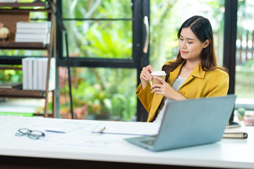 Tired of yawning, sleepy woman working at desk and holding coffee cup, overworked and sleep deprivation concept