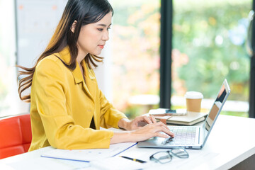 Portrait of pretty cheerful girl smiling while working on laptop in office