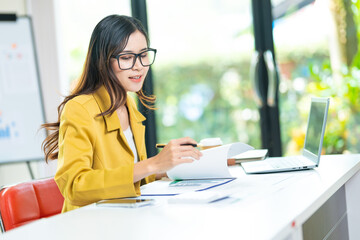 Fototapeta premium Portrait of pretty cheerful girl smiling while working on laptop in office