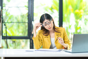 Fototapeta premium Asian women are stressed while working on laptop, Tired asian businesswoman with headache at office, feeling sick at work, copy space