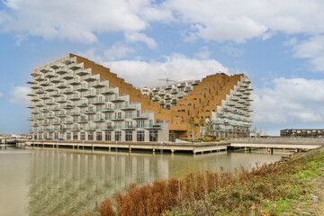 an apartment complex on the water's edge with buildings in the background and green vegetation...