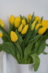 Bouquet of yellow flowers tulips against a white wall.	
