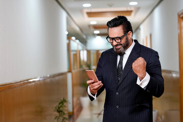 Indian corporate man smiling and winning expression after looking in smartphone some information.