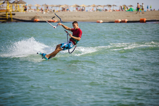 Professional Kiter Does The Difficult Trick. A Male Kiter Rides Against A Beautiful Background Of Waves And Performs All Sorts Of Maneuvers.