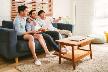 Gay people group sitting on the sofa, having popcorn and enjoying watching content on the tv in the living room. Three LGBT Caucasian and Asian people living together. Diversity of gay friendship.