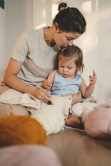 Woman hands holding embroidering needles while teaching her child to knit, at home on leisure time. People lifestyle portrait. Family home leisure. Family