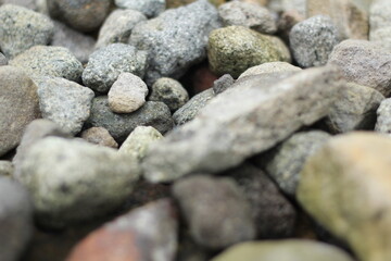 Natural rocks on the river bank. Pebbles and colored pebbles in water close-up. Texture of mixed different sizes stones on the shore of the river bank.