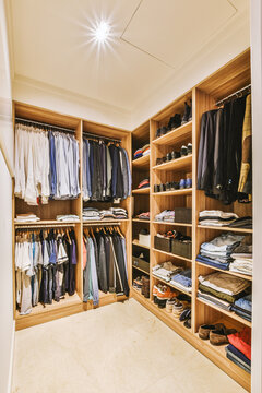 the inside of a walk - in closet with clothes and shoes hanging on wooden shelvings, showing how it's organized