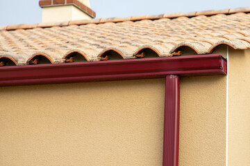 Roof showing red gutters and down pipe on new house facade