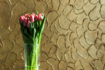 Bouquet of pink unopened tulips on a golden background.