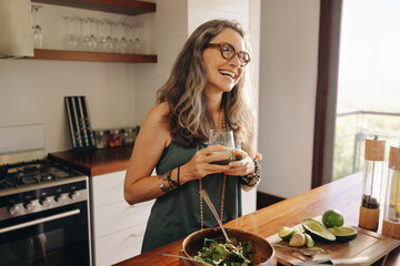 Happy vegan woman smiling while holding some green juice