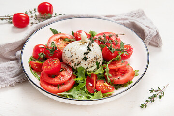 Delicious caprese salad with tomatoes and mozzarella cheese with fresh leaves. Italian food.