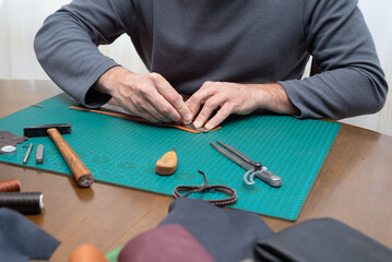 Close-up of male hands cutting out leather.