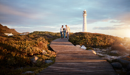 Lighthouse, family walking and nature adventure on a summer holiday at sunset by the sea. Ocean,...