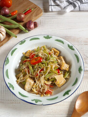 Stir fried bean, sprouts, and tofu is kind of easy to cook daily menu. Served in enamel plate on white wooden table with ingredients in background. Focus selection.