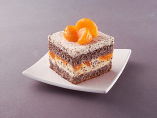 Mohnkuchen geschichtet mit Sahne und Mandarinen auf weissem Teller