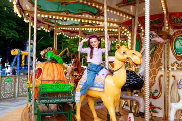 a child girl in an amusement park rides on a carousel and smiles with happiness, the concept of...