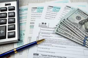 Fototapeta na wymiar 1040 blank individual income tax return, 2022 with dollar and calculator pen on desk