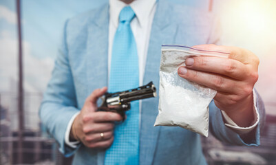 close up of man in suit holding gun pistol and  package with drugs cocaine