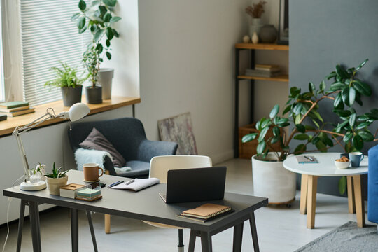 Horizontal image of modern workplace with laptop for remote work in the living room at home