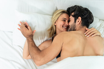Caucasian young man and woman starting foreplay and making love on bed. 