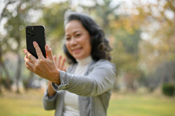 selective focus image, Happy 60s aged Asian woman is taking a selfie with her smartphone
